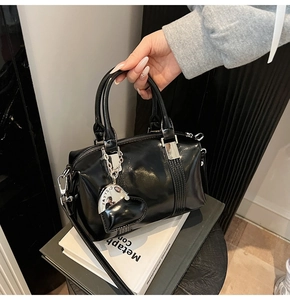 Close-up of a glossy black bowling bag featuring a heart-shaped silver metal charm