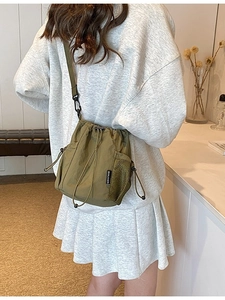 Olive green nylon drawstring bucket bag with mesh pocket and adjustable shoulder strap