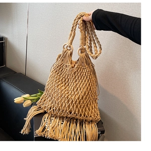 Gros plan d'un sac en paille bohème avec de longues franges et des anneaux en bois