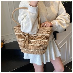 Detail of hand-woven straw tote with hollow diamond pattern and tassel pendant decor