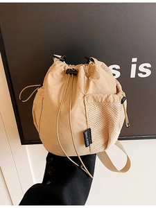 Lightweight beige nylon drawstring bucket bag with side mesh pocket and crossbody strap