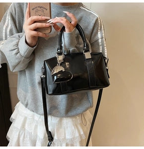 Close-up of black glossy patent leather bowling bag with heart charm and silver hardware