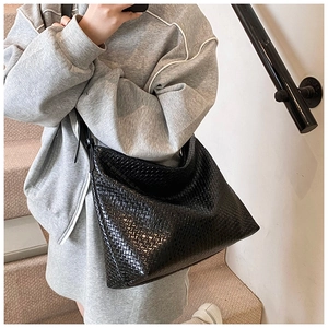 Close-up of black woven leather tote bag texture and slender shoulder straps