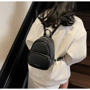 Rear view of a model wearing the mini black lychee leather backpack with slim straps