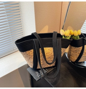 Détail d'un grand sac cabas bicolore en paille tressée avec anses noires