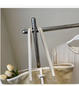 Détail du sac cabas en paille avec lanières en cuir blanc et fermoir en métal argenté