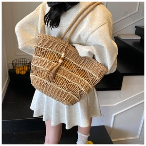 Detail of woven straw tote bag with yellow lining and bohemian wooden bead tassel