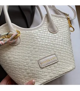 Gros plan d'un sac seau blanc tressé avec des détails dorés et le logo de la marque