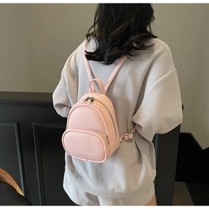 Pink mini faux leather backpack with adjustable straps worn by a model in a casual setting