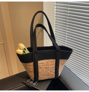 Détail du cabas tissé bicolore avec bandoulières noires et texture paille naturelle