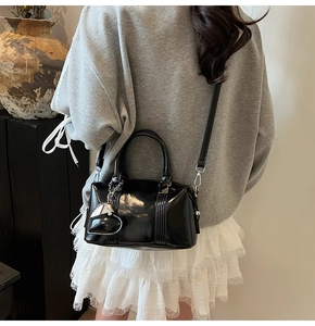 Chic black patent leather boston bag with a heart charm and elegant styling details