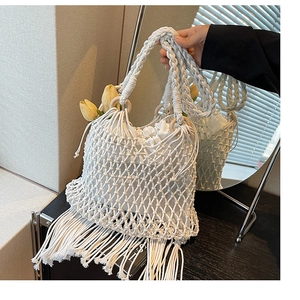 Détail d'un sac en paille blanche avec de longues franges et des anneaux en bois