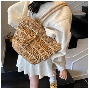 Detailed macro view of woven straw tote bag with decorative fringe and wood beads