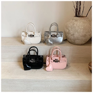 Miniature shell Kelly handbags in four colors with heart charms on stone steps