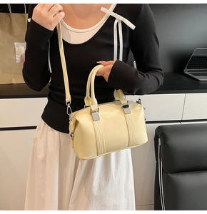 Macro view of creamy yellow Boston bag with glossy finish and silver hardware detail