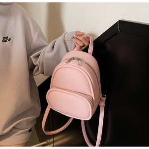 Close-up of pink mini backpack with textured faux leather and polished gold zippers
