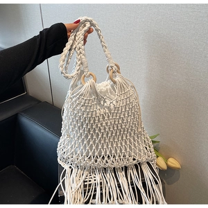 Détail d'un sac de plage au crochet blanc avec poignées en bois, franges et doublure