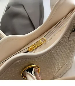Détail de la fermeture éclair dorée et de la texture tressée du sac seau beige