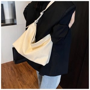Detailed shot showing the woven texture and adjustable strap of this cream hobo tote bag