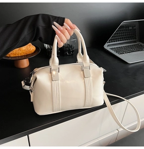 Close-up of cream Boston bag with vertical stitching and silver metal hardware