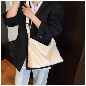 Detail of cream woven texture on a large faux leather tote bag with silver buckle strap