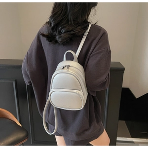 Mini silver PU leather backpack with lychee texture and dual zippers on a model