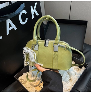 Avocadogrüne Handtasche mit Perlenanhänger in einer schwarzen Geschenkbox