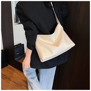Detail of cream woven shoulder bag showing strap attachment and premium PU texture
