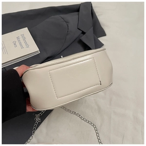 Detail view of reinforced stitching on off-white PU leather bag with silver chain strap