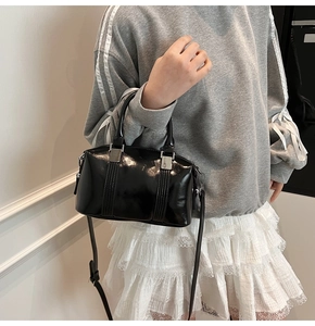 Detail of a black patent leather Boston bag featuring glossy finish and silver hardware
