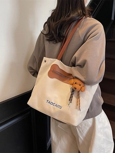 Off-white canvas tote bag with brown leather straps and cute puppy charm detail