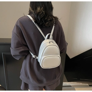 Detail of silver-grey mini backpack with lychee grain texture and metal zipper