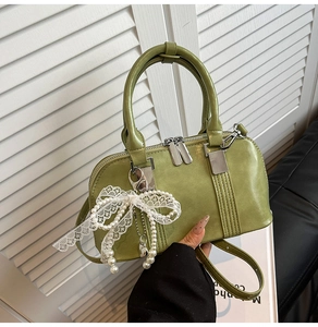 Detailansicht der grünen Lackleder-Tasche mit Perlen-Schleifen-Anhänger und Silberbeschlag