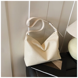 Detailed view of woven texture and adjustable strap on a cream-white hobo shoulder bag