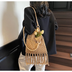 Sac à main en paille évidé beige avec de longues franges porté par un mannequin