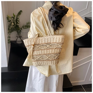 Detail of the woven texture and straw shoulder strap on a large summer beach tote bag