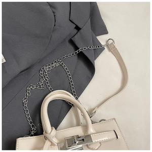 Close-up of beige Kelly-style handbag with silver hardware and dual strap options