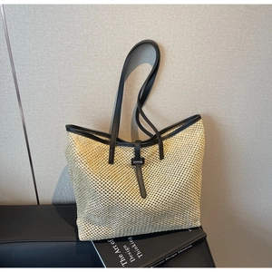 Détail du sac cabas en paille tissée avec bordure en cuir noir et boucle décorative