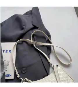 Detail of cream woven hobo bag with adjustable leather strap on a grey blazer