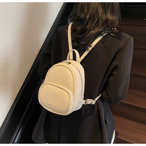 Detail of mini cream faux leather backpack showing pebbled texture and metal zippers