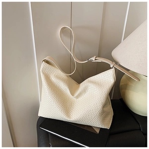Detail of beige tote bag with woven texture, adjustable strap and silver metal buckle