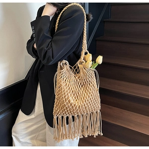 Détail du sac cabas en paille tissée avec motifs ajourés et pompons bohémiens