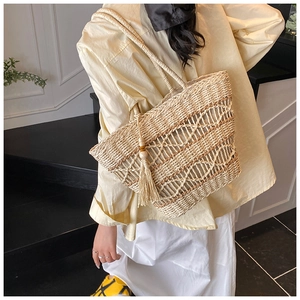 Detail of cream woven tote bag showing hollow-out diamond patterns and decorative tassels