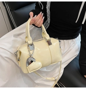 Detail of glossy cream yellow bowling bag with heart charm and silver zipper
