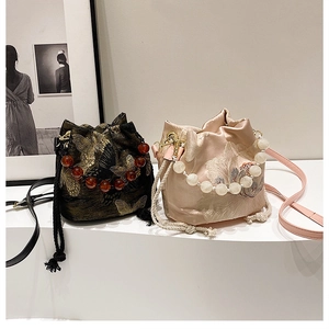 Detailed embroidery on vintage bucket bags with butterfly patterns and pearl handles