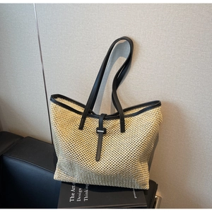 Vue détaillée du sac cabas en paille avec finitions en cuir sur fond minimaliste