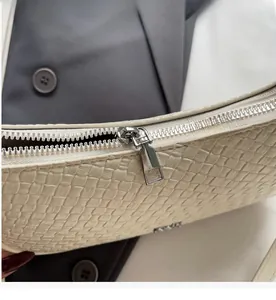 Close-up of silver metal zipper on cream woven textured shoulder bag for women