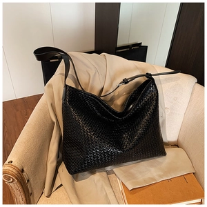 Detail of black woven leather hobo bag with adjustable strap and zipper on a sofa
