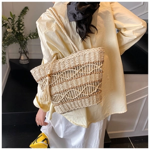 Detailed texture of woven straw tote bag with decorative tassels in a holiday setting