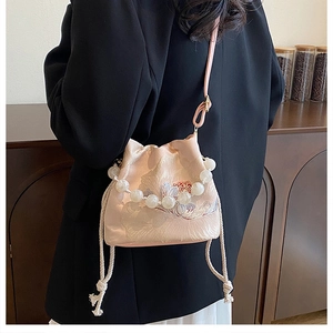 Detailed shot of pink satin bucket bag with floral embroidery and pearl handle